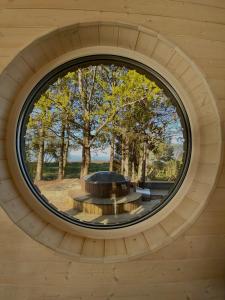 Holiday House "Sea Nest" في Kalni: نافذة مستديرة في مبنى خشبي مع طاولة مستديرة