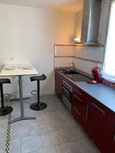 uma cozinha com um lavatório, uma mesa e bancos em Le Parmentier em Châlons-en-Champagne