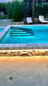 a blue swimming pool with two chairs at Aithonas Villa in Archangelos