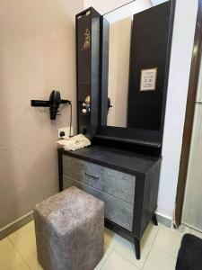 a bathroom with a dresser with a mirror and a stool at Cozy Stay At Raintown Taiping in Kamunting