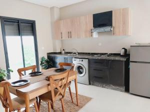 a kitchen with a wooden table and chairs in a kitchen at Appartement cosy proche Aéroport in Deroua