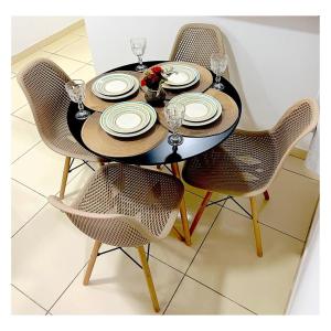 a table with two chairs and a table with plates and glasses at Apartamento Perto do Aeroporto in Lauro de Freitas