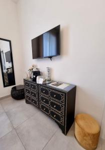 a black dresser with a flat screen tv on a wall at Dimora Giusti in Lecce