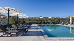 a swimming pool with lounge chairs and umbrellas at Brisot in Galatas