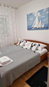 een slaapkamer met een bed en een schilderij van een zeilboot aan de muur bij Apartments Miro Omišalj in Omišalj