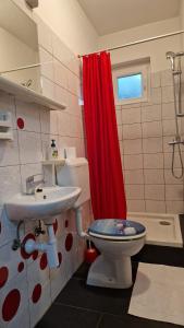een badkamer met een toilet, een wastafel en een rood douchegordijn bij Apartments Miro Omišalj in Omišalj