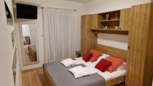 een slaapkamer met een bed met rode en witte kussens bij Apartments Miro Omišalj in Omišalj