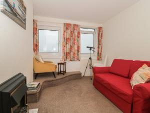 een woonkamer met een rode bank en een camera bij Bay View in Swanage