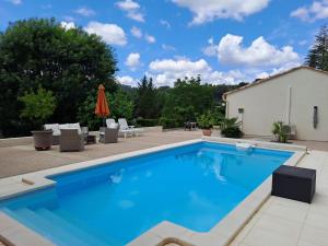 ein großer Pool mit Stühlen und einem Sonnenschirm in der Unterkunft chambre d'hôtes chez Jessica et Pascal in Barjols