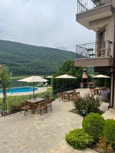 a patio with tables and umbrellas next to a pool at Eco House Kitana in Asparukhovo