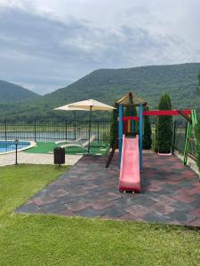 a playground with a slide and an umbrella at Eco House Kitana in Tschenge