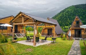 eine Blockhütte mit einer Terrasse mit einem Tisch und Stühlen in der Unterkunft Eco House Borjomi in Bordschomi