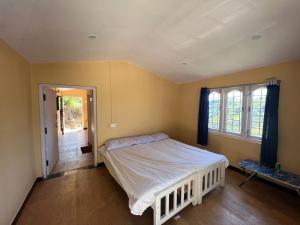 a bedroom with a white bed and a window at Heath Cote in Ooty