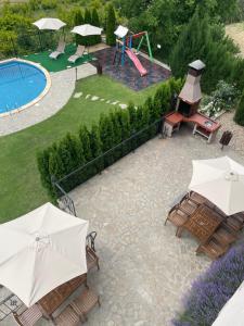 un patio avec un toboggan et une aire de jeux avec des parasols dans l'établissement Eco House Kitana, à Asparuhovo