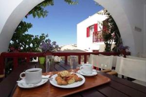 a table with cups and plates of food on a balcony at Akrogiali Hotel in Agios Sostis