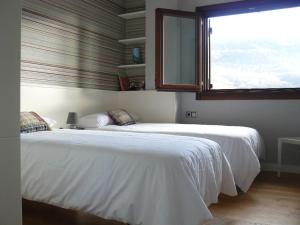 a bedroom with a large white bed with a window at Etxeondo in Torrano