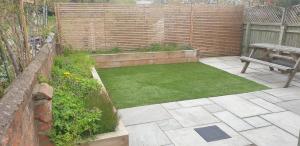 a small garden with a bench and grass at The Railway Inn - 3 Bedrooms in Milton Keynes