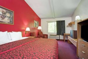 a hotel room with a bed and a red wall at Travelodge by Wyndham Red Wing in Red Wing