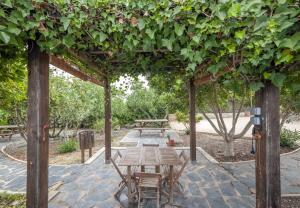 pergola ze stołem i krzesłami pod nim w obiekcie Alojamientos Rurales Berrocal w mieście Berrocal