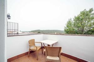 una mesa y sillas en un balcón con vistas en Alojamientos Rurales Berrocal, en Berrocal