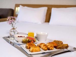 カルクフーにあるノボテル ナンテス カルクフーのベッドの上に朝食用の食品のトレイ