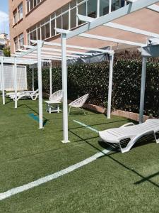 a group of white umbrellas and chairs on a lawn at APARTAMENTOS EL VELERO VIP in Torremolinos