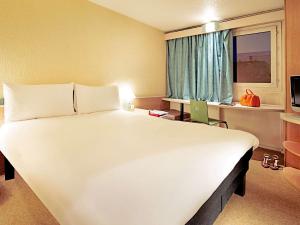 un grande letto bianco in una stanza con finestra di ibis London Heathrow Airport a Hillingdon