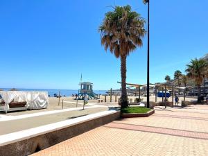 - une plage avec un palmier et une aire de jeux dans l'établissement Cozy Fuengirola apartment with sea view & pool, à Fuengirola