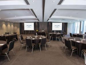 a conference room with tables and chairs and two screens at Quay West Suites Melbourne in Melbourne