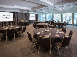 a conference room with tables and chairs and a screen at Quay West Suites Melbourne in Melbourne