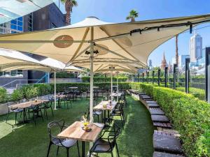 a restaurant with tables and chairs under a large umbrella at Quay West Suites Melbourne in Melbourne