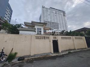 Best Inn Lahug في مدينة سيبو: منزل أمام جدار مع مبنى طويل