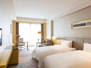 ChangshuにあるPullman Changshu Leemanのベッド2台とデスクが備わるホテルルームです。