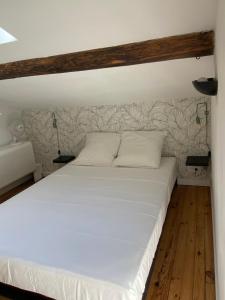 1 dormitorio con cama blanca y cabecero de madera en La Carretariá - Intra•muros - Wifi, en Aviñón