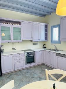 una cocina con armarios blancos y fregadero en Aphrodite sunshine suite en Mykonos ciudad