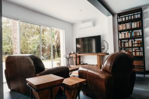 uma sala de estar com duas cadeiras e uma mesa e uma televisão em LA MAISON CACHEE-BA em La Teste-de-Buch