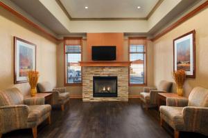 a waiting room with a fireplace and a flat screen tv at Days Inn & Suites by Wyndham Edmonton Airport in Leduc