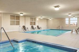 uma piscina num quarto de hotel com cadeiras e uma mesa em Days Inn & Suites by Wyndham Edmonton Airport em Leduc