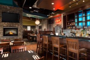 a restaurant with a bar with chairs and a fireplace at Days Inn & Suites by Wyndham Edmonton Airport in Leduc