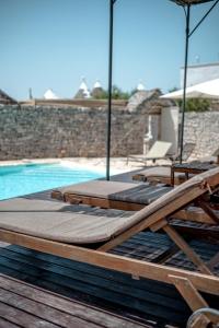a group of lounge chairs and a swimming pool at Masseria Pavone in Martina Franca