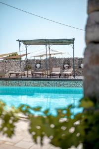 a swimming pool with chairs and a gazebo at Masseria Pavone in Martina Franca