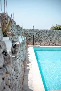 - une piscine à côté d'un mur en pierre dans l'établissement Masseria Pavone, à Martina Franca