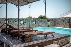 a swimming pool with a bunch of benches next to a stone wall at Masseria Pavone in Martina Franca
