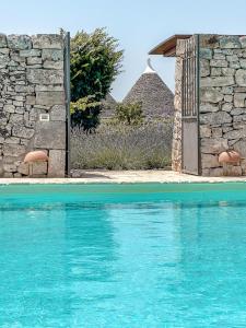une porte ouverte menant à un bâtiment en pierre et à une piscine dans l'établissement Masseria Pavone, à Martina Franca