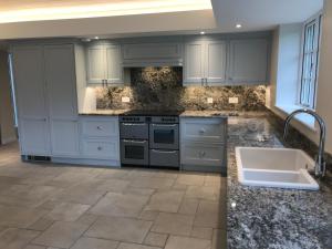 a kitchen with white cabinets and a sink at Charlton End - Goodwood Events in Chichester