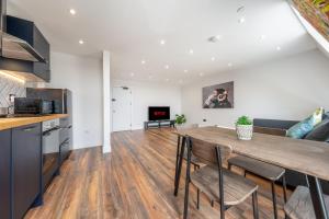 uma cozinha e sala de estar com uma mesa de madeira e cadeiras em 8 - West London Brand New Loft em Londres