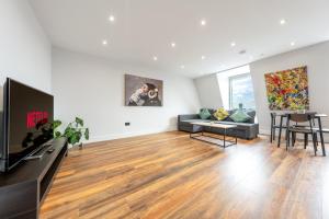 uma sala de estar com um sofá e uma televisão em 8 - West London Brand New Loft em Londres