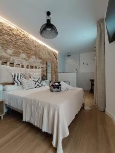 Un dormitorio con una gran cama blanca y una pared de ladrillo en El Tapial, en Chipiona