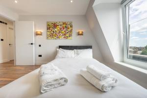 um quarto com uma cama branca e toalhas em 8 - West London Brand New Loft em Londres