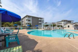 a swimming pool with chairs and a blue umbrella at Atlantic Beach Resort, a Ramada by Wyndham in Atlantic Beach
